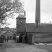 View from NNE showing main entrance and NNE front of clock tower with chimney in background