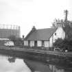 View from NNW showing WNW and NNE front of lock-keeper's cottage with gasholder in background