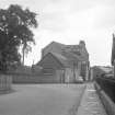 View looking SE showing workshops with main block of mill in background and with part of school in foreground