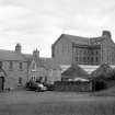 View from W showing SW front of houses with part of workshops in foreground and part of waterwheel house and main block of mill in background