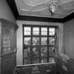 General view of staircase stained glass window, panelling and plaster pendant on ceiling. The window has a design of a town square.
Digital image of GW 2726