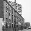 View from W showing SSW front of SE block of ironworks with tower block under construction in background