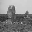 View from the south east of two large standing stones. Cup-marks visible on the stone on the right.
Original glass negative captioned 'Remains of Stone Circle at Springhill (formerly Gask) Skene / View from South East April 1906 / Stone in foreground 6 feet 3 inches above ground, greatest breadth 2 ft 9 in, distant stone 7 cup marks'.