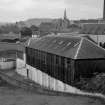 View from NNE showing NNW and ENE fronts of E block with chimney and W block of tannery and church in background