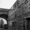 View from NE showing ESE front of warehouse with part of tenement in foreground and part of viaduct in background