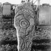 Inverurie Pictish symbol stone no.1, set upright.
Original print captioned: 'Sculptured Stone in Inverurie Churchyard No.I. Block of granite with 4 symbols viz. (1) Crescent and rod (2) Mirror case, (3) Serpent and rod (4) Double disc (on portion below ground). Figures in Stuarts 'Sculptured Stones  of Scotland' Vol. 1 pl. 113, and in 'Early Christian Monuments of Scotland' page 168.'