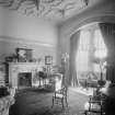 View of room adjoining library with marble fireplace and arch to bay window
