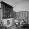 View of library with glazed bookcases surrounding marble fireplace with carved wooden overmantle
Digital iimage of B 64433