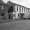 View from N showing WNW front of workshop with part of house in foreground