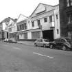 View from W showing NNW front of garage with stables and workshops in background and part of tenement in foreground