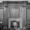 Detail of carved fireplace flanked by carved wooden corinthian pilasters.

