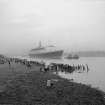 View looking SE showing QE II on River Clyde approaching Bowling with remains of pier in foreground