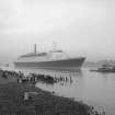 View looking South East showing QE II on the River Clyde approaching Bowling with remains of pier in foreground.