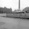 View from N showing part of NNW front of tenements with chimney of carpet factory dyeworks on left