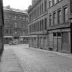 View from NE showing ESE front of warehouse with part of numbers 7-13 Shuttle Street on right and numbers 43-61 Ingram Street in background