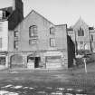 View from SE showing SSE front of warehouse with church in background and part of numbers 2-3 Trinty Quay on left