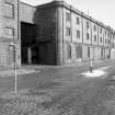 View from W showing SSW front and part of WNW front of E building with part of main building of flour mill in foreground and numbers 77-81 Waterloo Quay in background