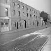 View from W showing SSW front of warehouse with part of numbers 77-80 in foreground