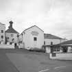 Bowmore Distillery
View from NE across E yard of distillery, showing NE side of maltings and kilns, the mash house and tun room, and (right) the visitors' centre.  Bowmore distillery is one of only two distilleries on Islay that continues to floor-malt its barley