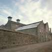 View from NW of main production block of distillery, showing ornate gables of the Tun Room and Mash House, with Malt Bins and Kilns in background, and Still House (R).
Digital image of C 64415 CN.