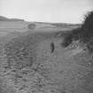 Copy of view of a man (R.J.C. Atkinson?) standing in the ditch of the Mote of Urr.