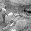 View of water mill with archaeologist hosing wooden timbers, during excavations by Brian Hope-Taylor.