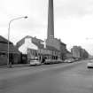 View from SSE showing factory chimney with E front of public house in middle foreground