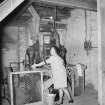 Interior
View showing woman working on 'baby' brick-making machine