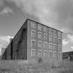 Digital image of a view from WSW of SW end of 4-storeyed Mule Spinning Mill (building B6), with former Weaving Shed (building B1) in distance (right)