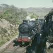 View from E showing locomotive 64592 and another locomotive behind approaching station