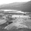 View of Mullardoch-Fasnakyle-Affric Project, contract no 9, Mullardoch Dam. View from north west showing stockpiles and reconstructed cement shed.
Scan of glass negative no. 133, 873/1