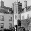 View of re-entrant angle of Innergellie house with well dressed lady on stair and ladies posing with parasols on the parapet.