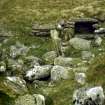 Interior of hut (BL00 98) showing (in foreground) edge-set backstone of hearth beside doorway and (in background) aumbry in NW wall. View from SE.