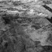 Oblique aerial view centred on the remains of a field system, rig, enclosures and rig at Burn of Keenie, looking to the NNW.