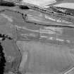 Oblique aerial view centred on the cropmarks of the enclosure, rig, pits and possible rectangular buildings at Legatesden, looking to the SSE.

