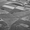 Oblique aerial view centred on the cropmarks of the unenclosed settlement, ring ditches, pits and rig at Bloodymire, looking to the SW.