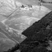 Oblique aerial view centred on the cropmarks of an unenclosed settlement, ring ditches, enclosures and pits at Craigston Castle with Fintry farmstead adjacent, looking to the WSW.