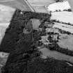 Oblique aerial view centred on Craigston Castle with the cropmarks of an unenclosed settlement, ring ditches, enclosures and pits adjacent, looking to the WNW.