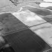 Oblique aerial view centred on the cropmarks of a palisaded enclosure, ring ditches, pits and rig at Suttie, looking to the SW.