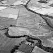 Oblique aerial view centred on the cropmarks of the unenclosed settlement, ring ditches, pits and rig with Stracathro Roman Fort and Temporary Camp adjacent at Smiddyhill, looking to the WNW.