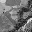 Oblique aerial view centred on the cropmarks of rig, a possible enclosure or long barrow at Rothes with Glenrothes Distillery adjacent, looking to the WSW.

