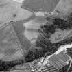 Oblique aerial view centred on the cropmarks of rig, a possible enclosure or long barrow at Rothes with Glenrothes Distillery adjacent, looking to the SW.

