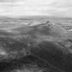 Oblique aerial view centred on the remains of the fort at Mither Tap of Bennachie, looking to the NE.