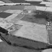 Oblique aerial view centred on the cropmarks of the unenclosed settlement, soutterain, enclosures and barrow at Boysack Mills with the Waulkmill and Boysack quarries adjacent, looking to the NNE.