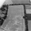 Oblique aerial view centred on the cropmarks of the palisaded settlement, roundhouse, possible barrows and linear features at Priestfield, with the walled garden at Anniston House adjacent,looking to the WSW.