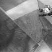 Oblique aerial view centred on the cropmarks of the souterrains and rig with the farmstead adjacent at Upper Powburn, looking to the N.