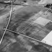 Oblique aerial view centred on the cropmarks of the roundhouses and ring ditches of the unenclosed settlement with the farmstead adjacent at Newbigging, looking to the WNW.