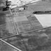 Oblique aerial view centred on the cropmarks of the roundhouses and ring ditches of the unenclosed settlement at Newbigging, looking to the N.