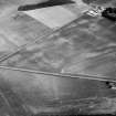 Oblique aerial view centred on the cropmarks of the roundhouses and ring ditches of the unenclosed settlement with the farmstead adjacent at Newbigging, looking to the NE.