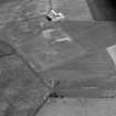 Oblique aerial view centred on the cropmarks of the barrow and the rectangular building at Newton of Lewesk, looking to the WSW.